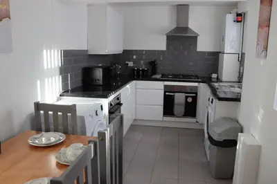 a kitchen with white appliances and a wooden table at Anfield 5bed 5bath cosy group retreat in Liverpool
