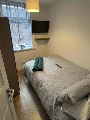 a bedroom with a bed with two blue pillows on it at Anfield 5bed 5bath cosy group retreat in Liverpool