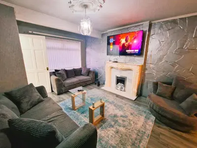 a living room with a fireplace and a tv on a stone wall at Amazing Spacious 3BDR Home Near LFC Stadium in Liverpool