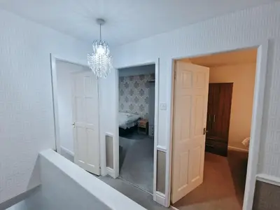 a hallway with a chandelier and a room with a bed at Amazing Spacious 3BDR Home Near LFC Stadium in Liverpool