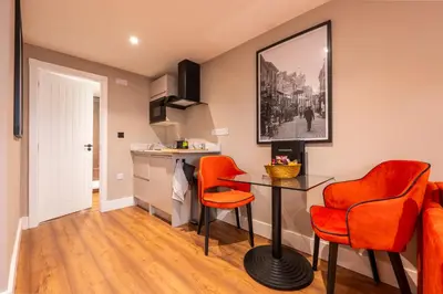 a living room with orange chairs and a table at The Terrace - A St David Aparthotel in Barrow