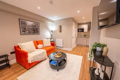 a living room with an orange couch and a table at The Terrace - A St David Aparthotel in Barrow