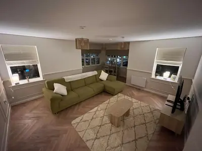 a living room with a green couch and two windows at Sustainable Habitats- Berkley House apartment in Blackpool