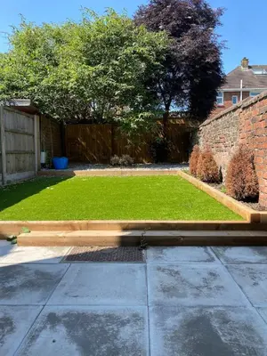 a garden with a lawn and a brick wall at Slick Space for a Wigan Stay - 5 Minutes from M6 and M58 Motorways in Pemberton