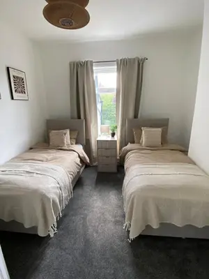 two beds in a room with a window at Slick Space for a Wigan Stay - 5 Minutes from M6 and M58 Motorways in Pemberton