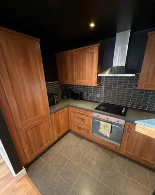 a kitchen with wooden cabinets and a stove top oven at Central Liverpool 2-Bed Balcony Apartment by StaySavvy Accommodation in Liverpool