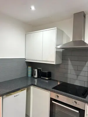 a kitchen with white cabinets and a stove top oven at Cosy flat Lytham St Annes - Sleeps 2 with parking in Lytham St Annes