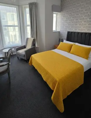 a bedroom with a large bed with a yellow blanket at Sunset Suites in Blackpool