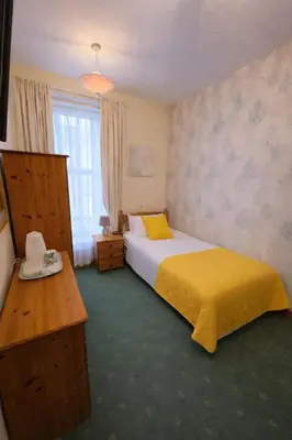 a bedroom with a bed and a yellow blanket at Sunset Suites in Blackpool