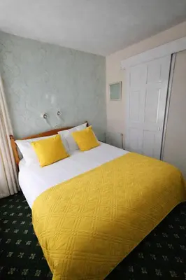 a bedroom with a large bed with yellow sheets at Sunset Suites in Blackpool