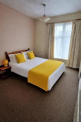 a bedroom with a large bed with yellow sheets and a window at Sunset Suites in Blackpool