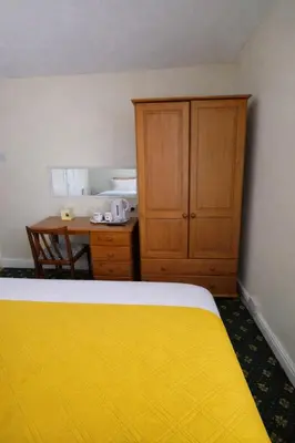 a bedroom with a yellow bed and a wooden cabinet at Sunset Suites in Blackpool