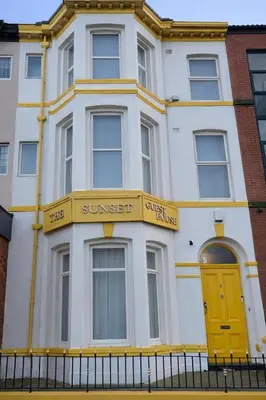 a white building with a yellow door on a street at Sunset Suites in Blackpool