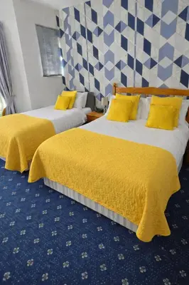two beds in a hotel room with yellow sheets at Sunset Suites in Blackpool