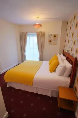 a bedroom with a large bed with yellow pillows at Sunset Suites in Blackpool