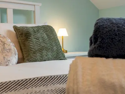 a bedroom with a bed with green pillows and a lamp at Large House in Central Ulverston Sleeps 10 - Pass the Keys in Ulverston