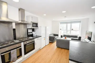 a kitchen and living room with a stove and a couch at Modern & Convenient 4 Bed Apartment in Liverpool in Liverpool