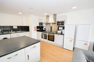 a large kitchen with white appliances and wooden floors at Modern & Convenient 4 Bed Apartment in Liverpool in Liverpool
