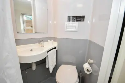 a bathroom with a sink and a toilet and a mirror at Modern & Convenient 4 Bed Apartment in Liverpool in Liverpool