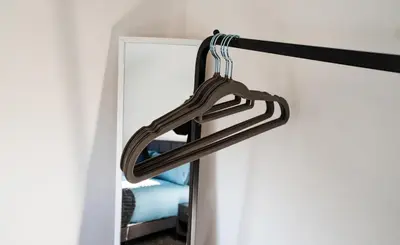 a closet with a wooden hanger next to a mirror at Cosy & Stylish Home in St Helens