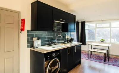 a kitchen with a sink and a washing machine at Cosy & Stylish Home in St Helens