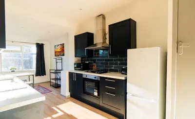 a kitchen with black cabinets and a white refrigerator at Cosy & Stylish Home in St Helens
