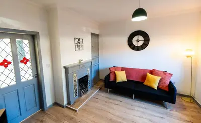 a living room with a black couch and a fireplace at Cosy & Stylish Home in St Helens