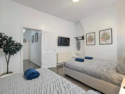 a bedroom with two beds and a tv on the wall at Large 2-Bed Near City Centre & Anfield Parking in Liverpool