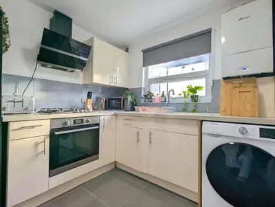 a kitchen with white cabinets and a washer and dryer at Large 2-Bed Near City Centre & Anfield Parking in Liverpool