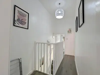 a hallway with white walls and a staircase with pictures at Large 2-Bed Near City Centre & Anfield Parking in Liverpool