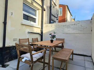 a wooden table and chairs with flowers on a patio at Large 2-Bed Near City Centre & Anfield Parking in Liverpool