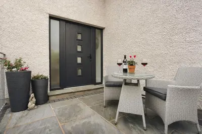 a patio with a table and chairs and a door at The Lookout - Ridgestone in Grange Over Sands