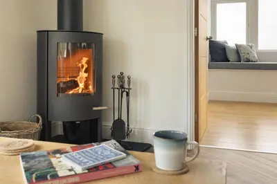 a living room with a fireplace and a table at The Lookout - Ridgestone in Grange Over Sands