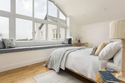 a white bedroom with a large window and a bed at The Lookout - Ridgestone in Grange Over Sands