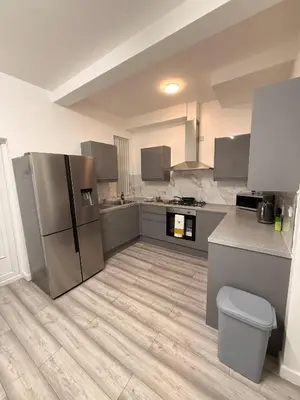 a kitchen with stainless steel appliances and a wooden floor at Stylish Dream Home with 4 en-suite Bedrooms in Liverpool