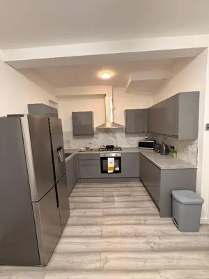 a large kitchen with stainless steel appliances and gray cabinets at Stylish Dream Home with 4 en-suite Bedrooms in Liverpool