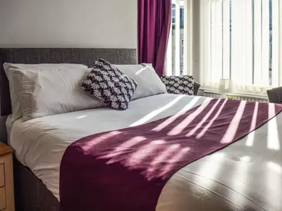 a bed with a purple and white blanket on it at Contractor's Rest in Blackpool