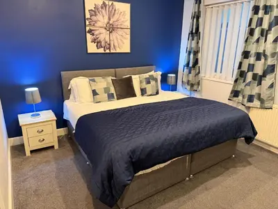 a bedroom with a large bed with blue walls at Contractor's Rest in Blackpool