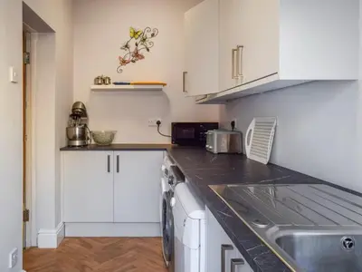 a kitchen with white cabinets and a sink at Contractor's Rest in Blackpool