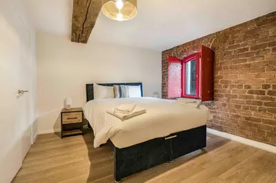 a bedroom with a large bed and a brick wall at GuestReady - Cozy retreat in vibrant Liverpool in Liverpool