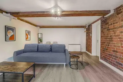 a living room with a couch and a brick wall at GuestReady - Cozy retreat in vibrant Liverpool in Liverpool