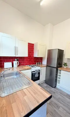 a kitchen with white cabinets and a stainless steel refrigerator at Deepdale House - Comfortable 2 Bedroom Home near Major Attractions in Preston in Preston
