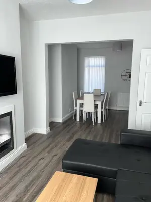a living room with a black couch and a table at Spacious Home From Home, Parking, Contractors in Liverpool