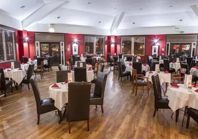 a restaurant with white tables and chairs and red walls at Swanmere lodge, Lakeside view Pinelake Carnforth in Carnforth