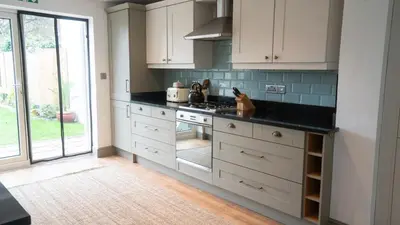 a kitchen with white cabinets and a black counter top at Welcoming 3 bed home in Formby