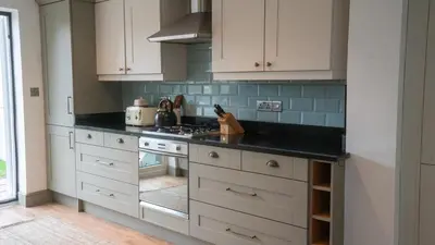 a kitchen with white cabinets and a black counter top at Welcoming 3 bed home in Formby
