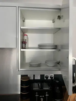 a kitchen with white cabinets and plates on shelves at The Works Apartments in Liverpool