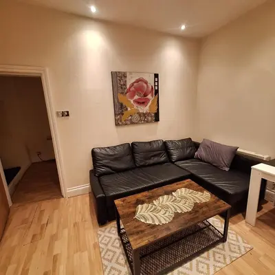 a living room with a black couch and a table at Spacious 2BR, 5 Min Walk to Anfield, Free Parking in Liverpool