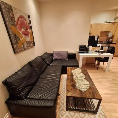 a living room with a black leather couch and a table at Spacious 2BR, 5 Min Walk to Anfield, Free Parking in Liverpool