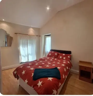 a bedroom with a bed with a red comforter and a window at Spacious 2BR, 5 Min Walk to Anfield, Free Parking in Liverpool